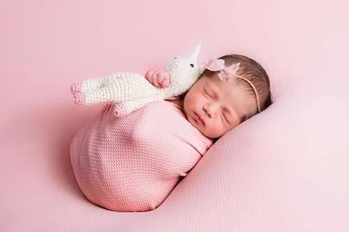 Bebé durmiendo con unicornio de peluche