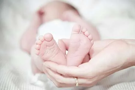 Pies de bebé en manos de un adulto